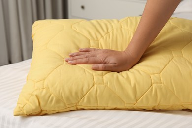 Photo of Woman touching soft pillow in bedroom, closeup