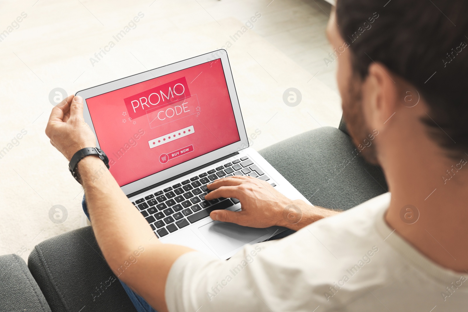 Photo of Man holding laptop with activated promo code on sofa, closeup