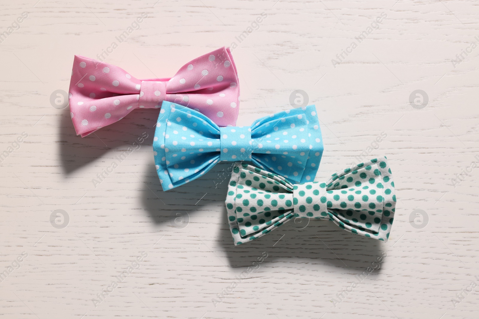 Photo of Stylish color bow ties on white wooden table, flat lay