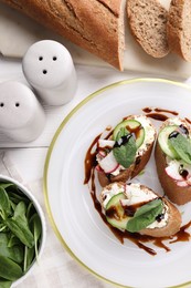 Photo of Delicious bruschettas with cream cheese, vegetables, balsamic vinegar and ingredients on white table, flat lay