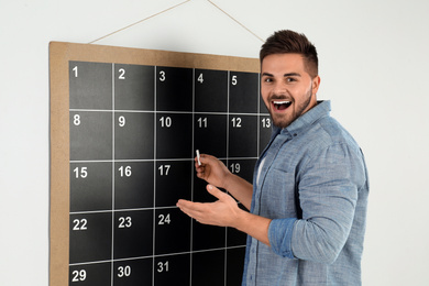 Photo of Young man writing with chalk on board calendar