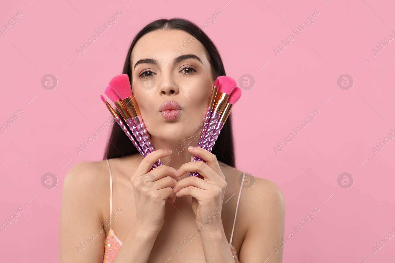 Photo of Beautiful woman with different makeup brushes on pink background