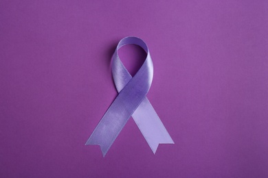 Photo of Purple awareness ribbon on color background, top view