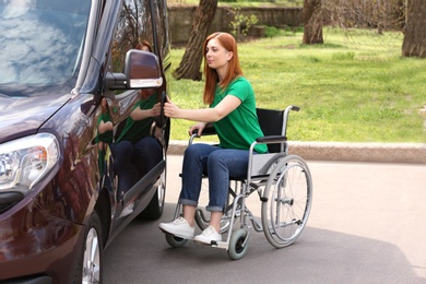 Woman in wheelchair opening door of her van outdoors