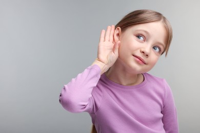 Photo of Little girl with hearing problem on grey background. Space for text