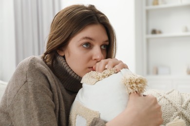 Photo of Sad young woman sitting on sofa at home