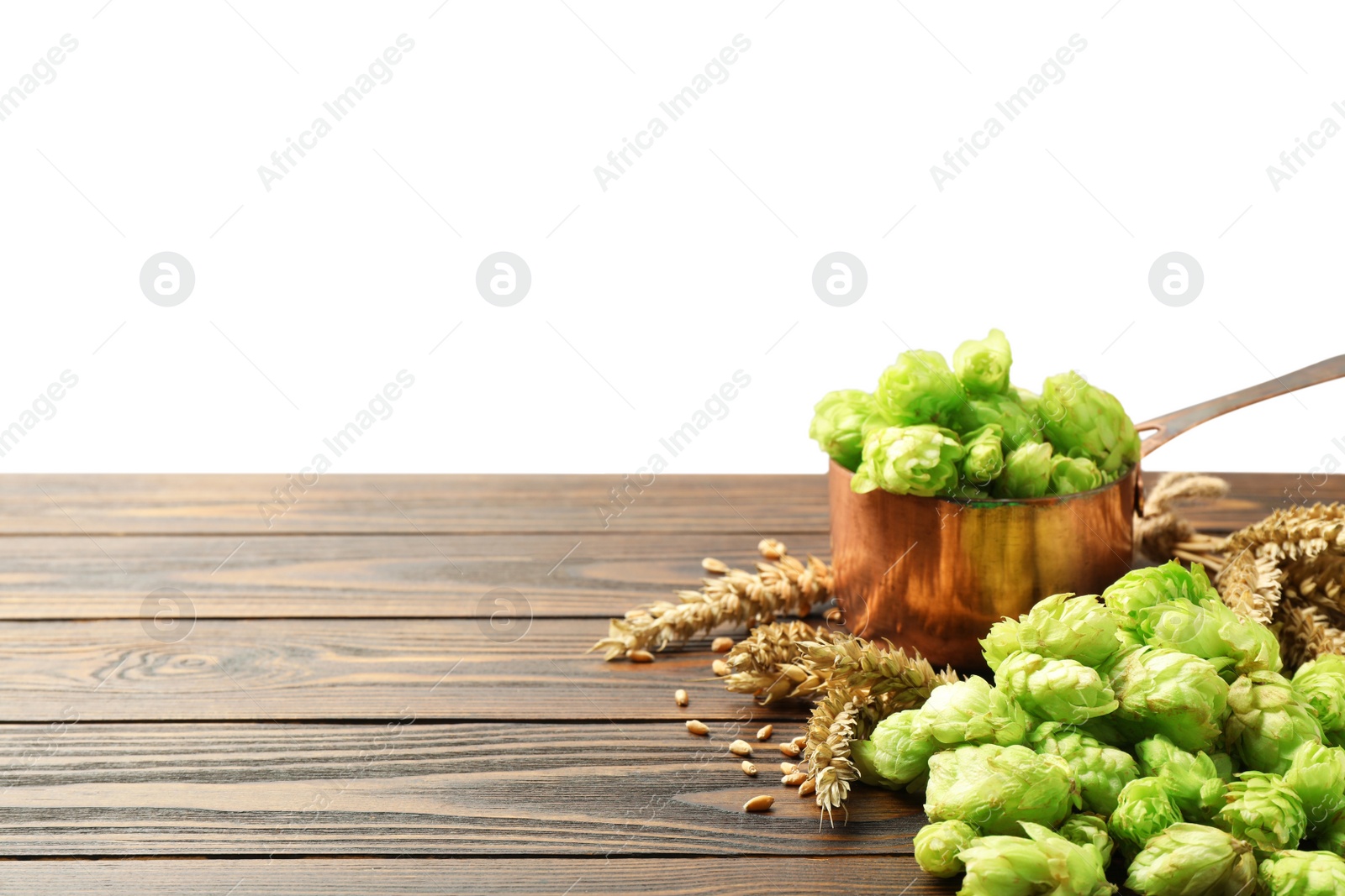 Photo of Fresh hop flowers and wheat ears on wooden table against white background, space for text