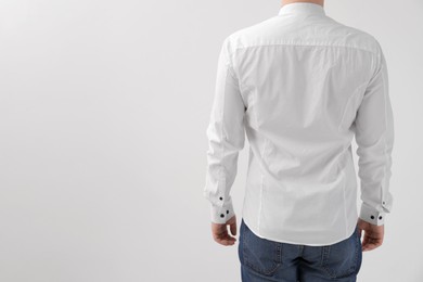 Man wearing rumpled shirt on white background, back view