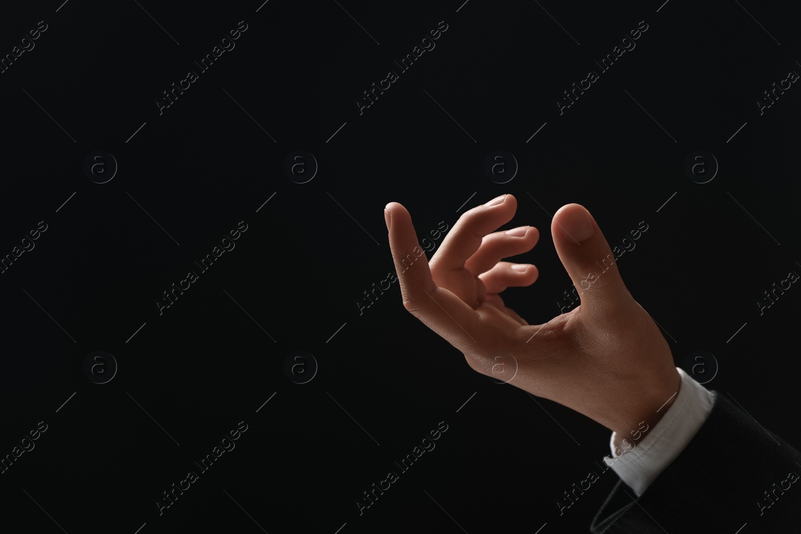 Photo of Man holding something in hand on black background, closeup. Space for text