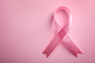 Pink ribbon on color background, top view with space for text. Breast cancer awareness concept