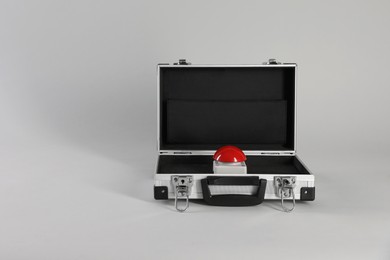 Photo of Red button of nuclear weapon in suitcase on light gray background, space for text. War concept