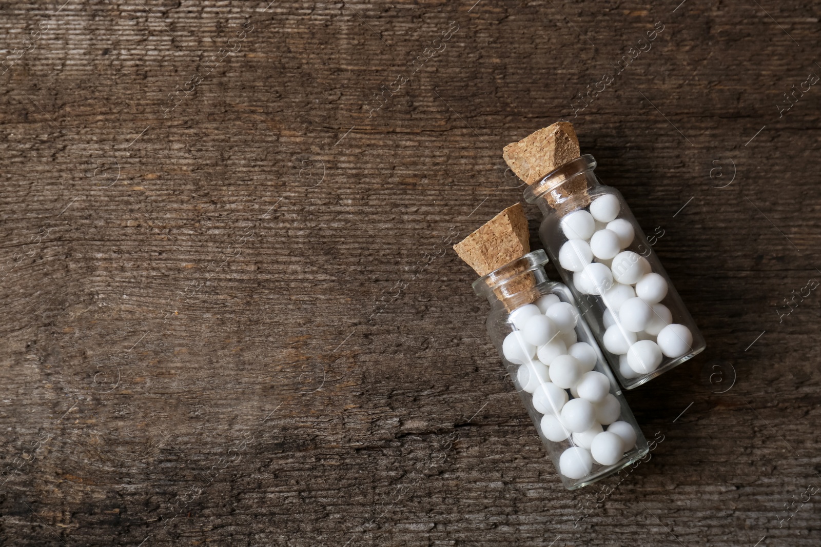 Photo of Bottles of homeopathic remedy on wooden background, flat lay. Space for text