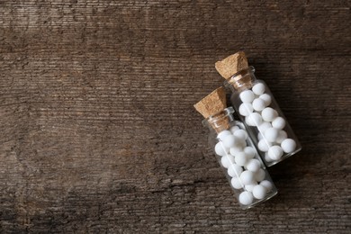 Photo of Bottles of homeopathic remedy on wooden background, flat lay. Space for text