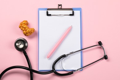 Photo of Endocrinology. Stethoscope, clipboard, model of thyroid gland and pen on pink background, flat lay