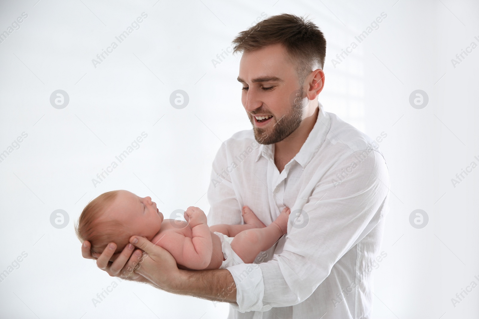 Photo of Father with his newborn son on light background