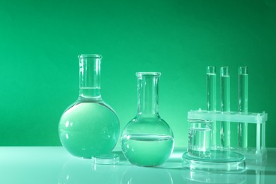 Photo of Laboratory analysis. Different glassware on table against green background