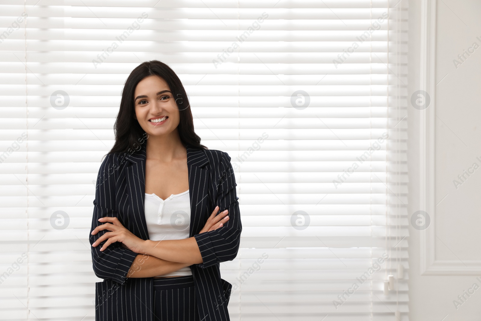 Photo of Beautiful woman in formal suit near window, space for text. Business attire