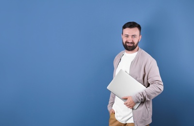 Photo of Portrait of handsome bearded man with laptop on color background