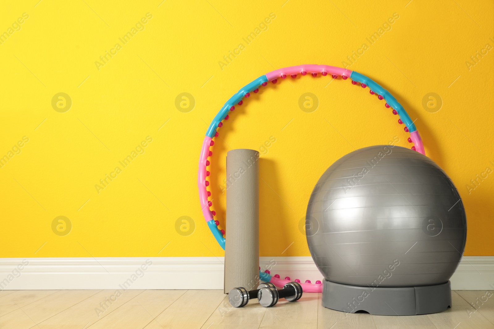 Photo of Set of fitness inventory on floor near yellow wall, space for text. Rehabilitation medicine