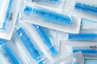 Photo of Packed disposable syringes with needles on light blue background, top view