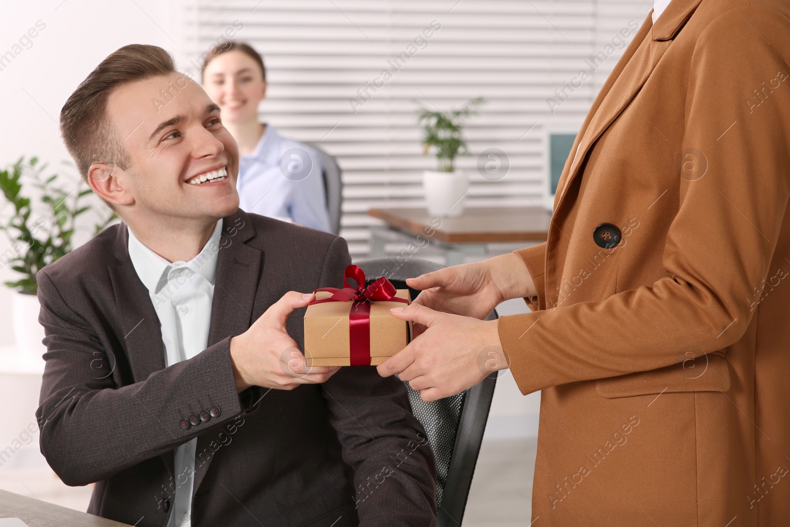 Photo of Woman presenting gift to her colleague in office