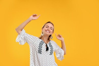 Photo of Portrait of smiling hippie woman dancing on yellow background
