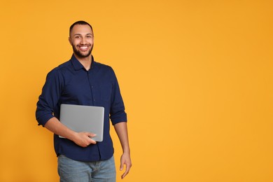 Photo of Smiling young man with laptop on yellow background, space for text