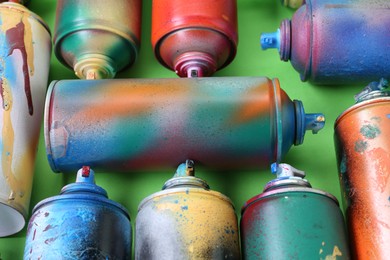 Photo of Many spray paint cans on green background