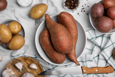 Photo of Different types of fresh potatoes on white marble table, flat lay