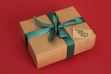 Photo of Happy Father's Day. Gift box and card with greetings on red background, closeup