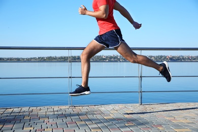 Sporty man running outdoors on sunny morning