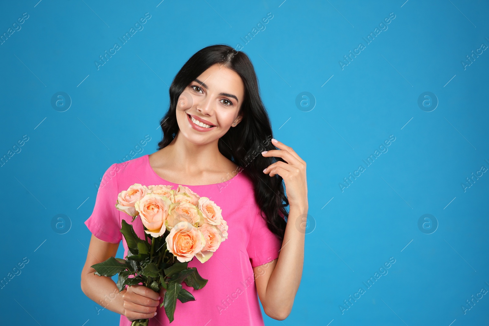 Photo of Portrait of smiling woman with beautiful bouquet on light blue background