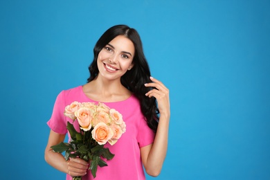 Portrait of smiling woman with beautiful bouquet on light blue background