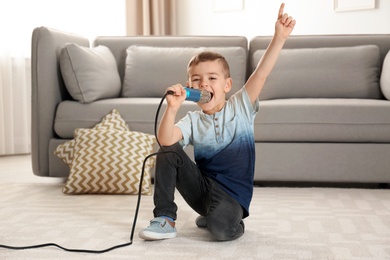 Photo of Cute funny boy with microphone in living room