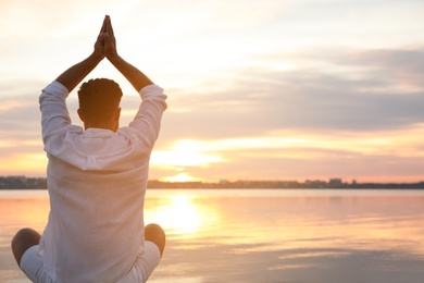 Man near river at sunset, space for text. Nature healing power