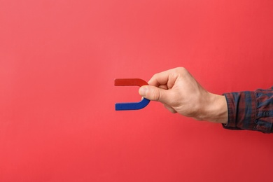 Man holding magnet on color background, closeup. Space for text