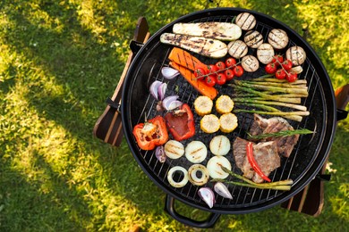 Photo of Delicious grilled vegetables and meat on barbecue grill outdoors, top view. Space for text