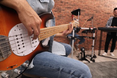 Man playing electric guitar during rehearsal in studio, closeup. Music band practice