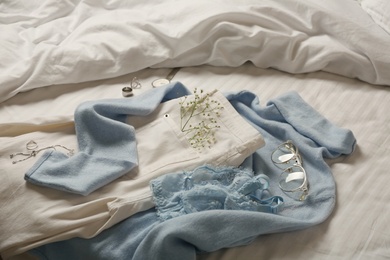 Photo of Stylish look with cashmere sweater. Women's clothes and accessories on bed