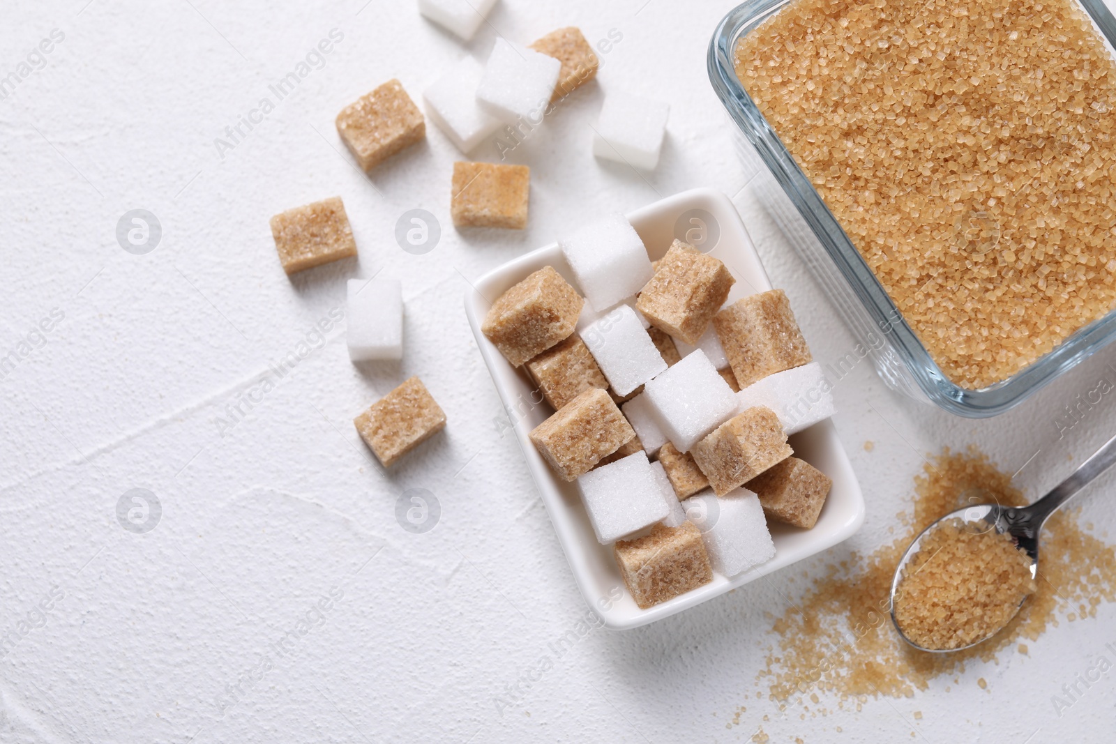 Photo of Bowls and spoon with different types of sugar on white table, flat lay. Space for text