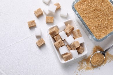 Bowls and spoon with different types of sugar on white table, flat lay. Space for text