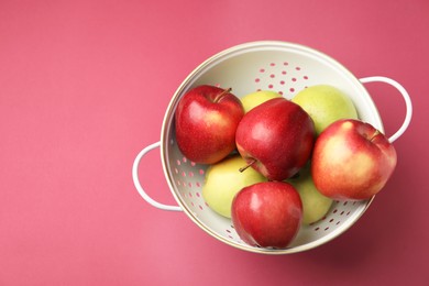 Photo of Colander with fresh apples on pink table, top view. Space for text