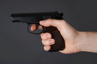 Photo of Man aiming gun on dark background, closeup