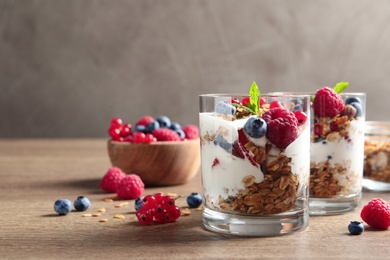 Image of Tasty dessert with yogurt, berries and granola on wooden table, space for text 