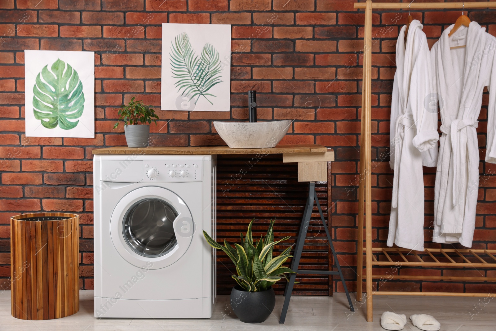 Photo of Washing machine and wooden rack with terry bathrobes indoors. Laundry room interior design