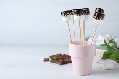 Photo of Delicious marshmallows covered with chocolate on white wooden table. Space for text