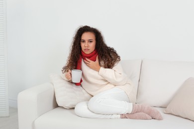 Sick African American woman with cup of hot drink at home