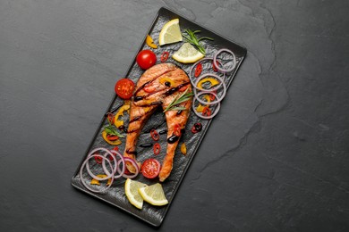 Tasty salmon steak served on black table, top view