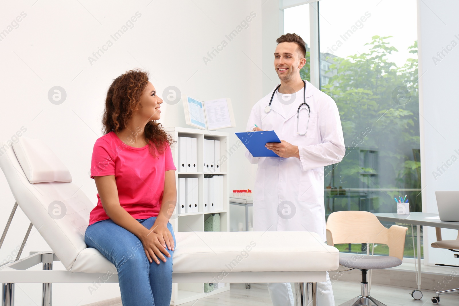 Photo of Male doctor working with African American patient in hospital