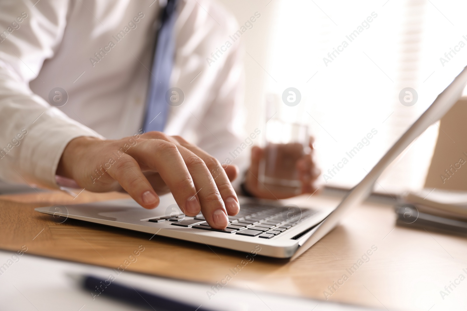 Photo of Man working with laptop in office, closeup of hand